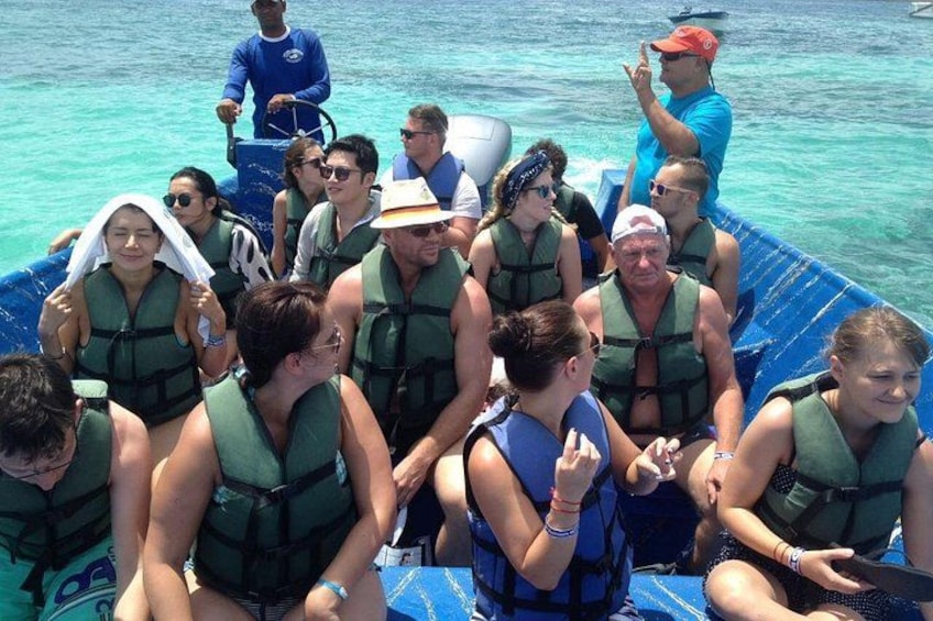 A group of people on a blue boat wearing life jackets, with clear blue water in the background. 2