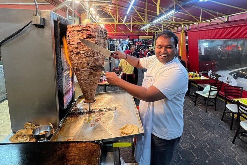 Una persona che affetta la carne da una rosticceria verticale. 3