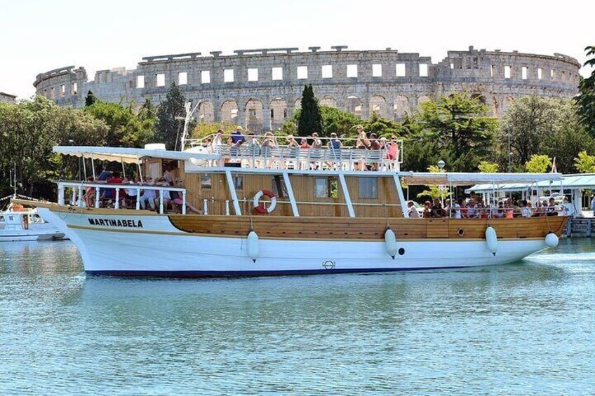 A boat named MARTINABELA docked near a historic building. 1