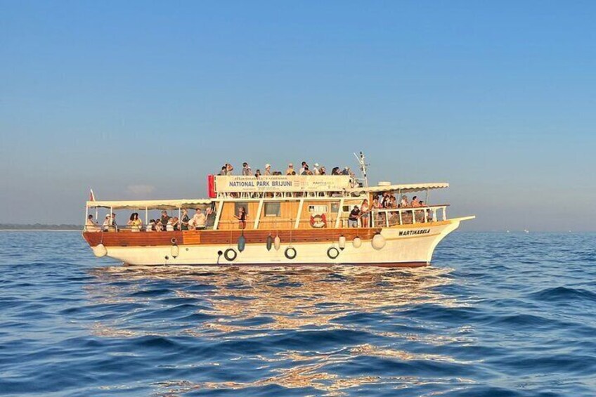 A boat with passengers, labeled "NATIONAL PARK BRUJUNI," on a body of water. 2