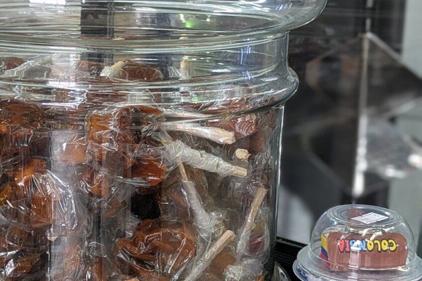 A glass jar filled with wrapped items, possibly food, and a small plastic container with a label. 3