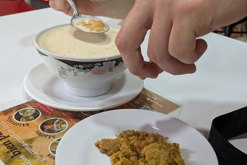 A person serving a creamy soup from a floral-patterned bowl onto a white plate. 2