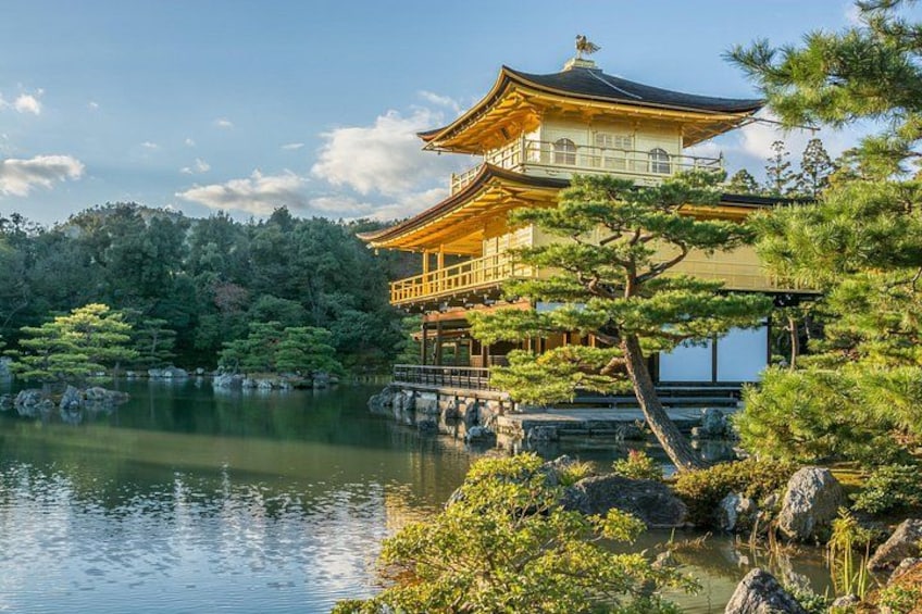 En traditionel japansk bygning med et gyldent tag, omgivet af en rolig sø og frodig vegetation. 5