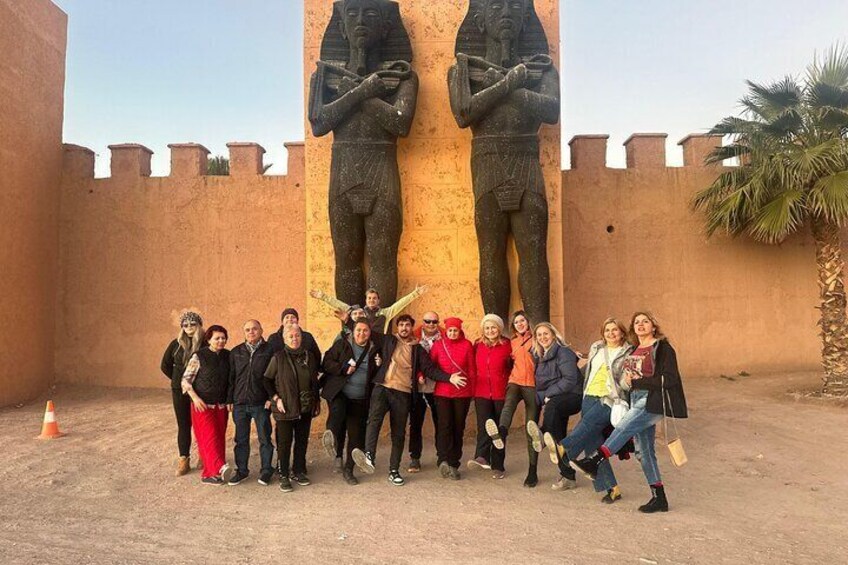 A group of people posing in front of a large ancient Egyptian statue. 1