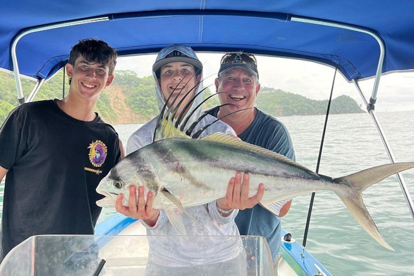 Three people on a boat holding a large fish. 1