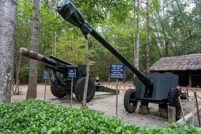 A cannon in a forested area with a sign indicating its historical significance. 2