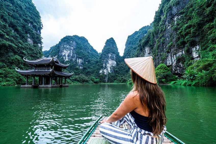 A person in a boat with a traditional conical hat, a pagoda, and a mountainous landscape. 4
