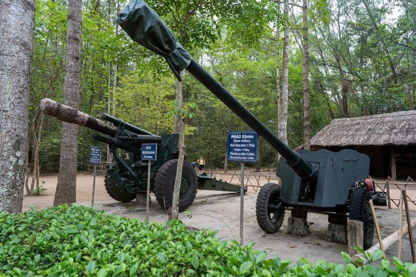 A cannon in a forested area with a sign indicating its length. 2