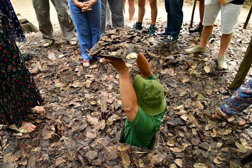 A person sitting on the ground surrounded by dry leaves, with others standing nearby. 3