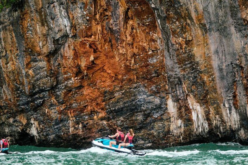 A boat with two people on a river with rocky cliffs in the background. 3
