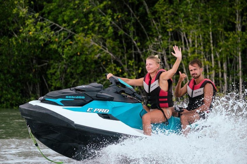 Two people on a jet ski with water splashing around them. 1