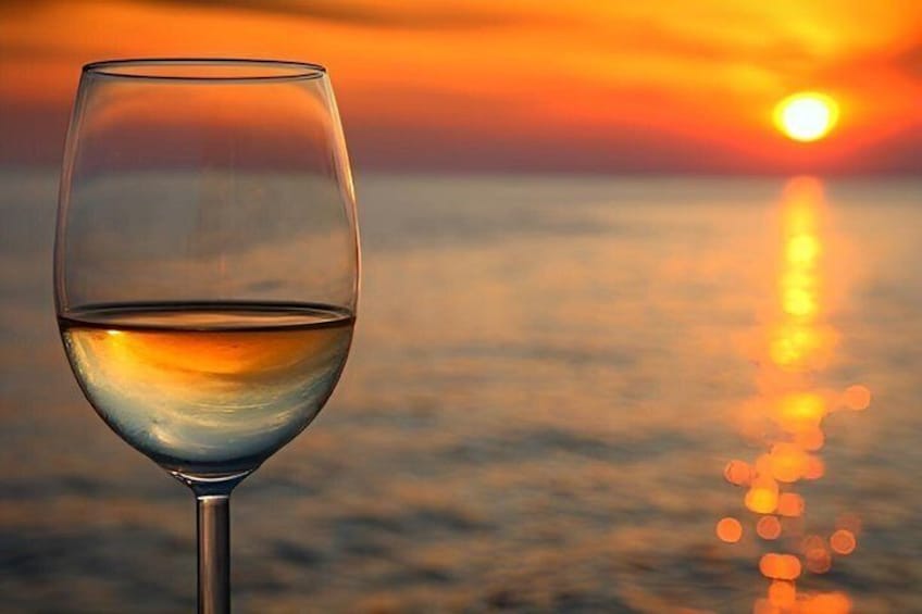 A glass of white wine with a sunset in the background. 4