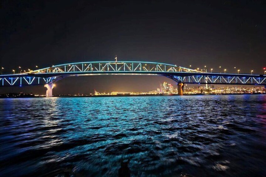 A nighttime view of a bridge with illuminated blue lights over a body of water. 3