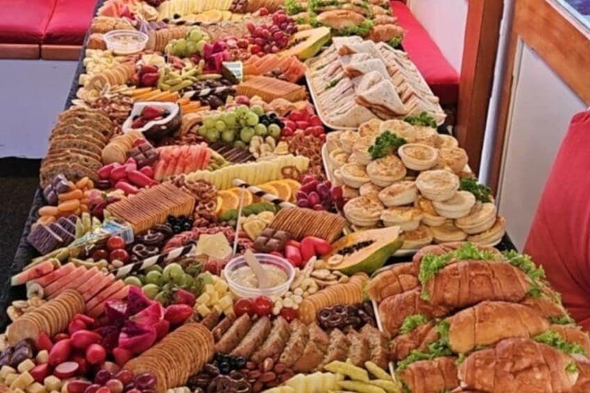 A table with various food items including sandwiches, fruits, and pastries. 5
