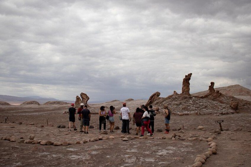 A group of people standing on a rocky terrain with unique rock formations in the background. 3
