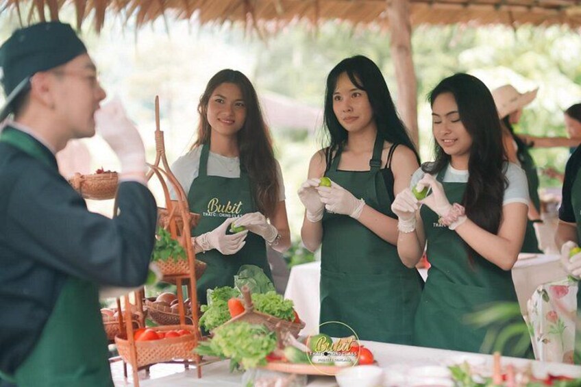 People wearing green aprons preparing food outdoors. 4