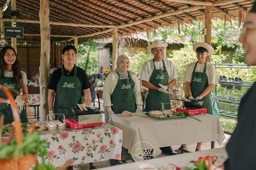 People wearing aprons with the word 'Batik' serving food at an outdoor market. 1