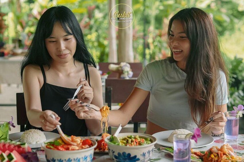 Two people dining at an outdoor table with various dishes and drinks. 2