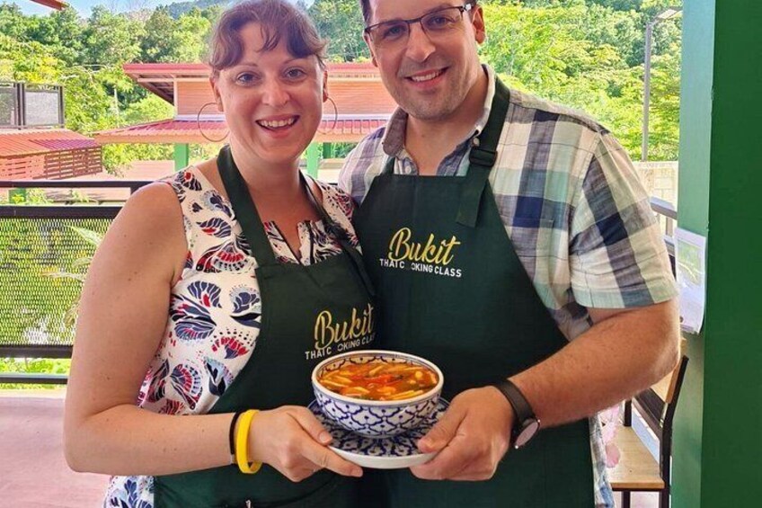 Two people wearing aprons with the Bukit logo, holding a bowl of food. 4