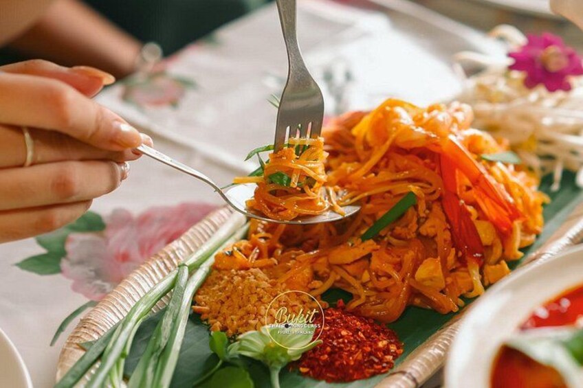 A person eating a dish with noodles and vegetables, with a fork in hand. 3