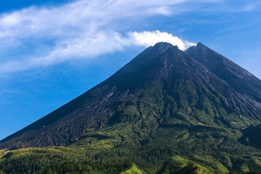 A mountain with a peak, lush green vegetation, and a clear sky. 2
