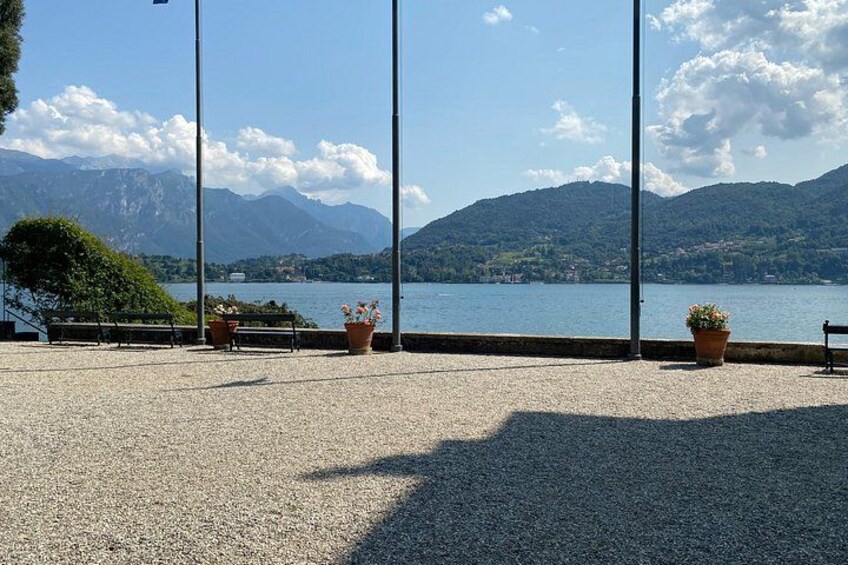 A lakeside promenade with potted plants, a bench, and a view of mountains. 4