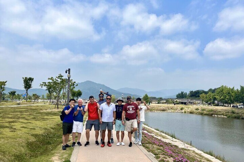 A group of people standing on a path by a lake with mountains in the background. 5