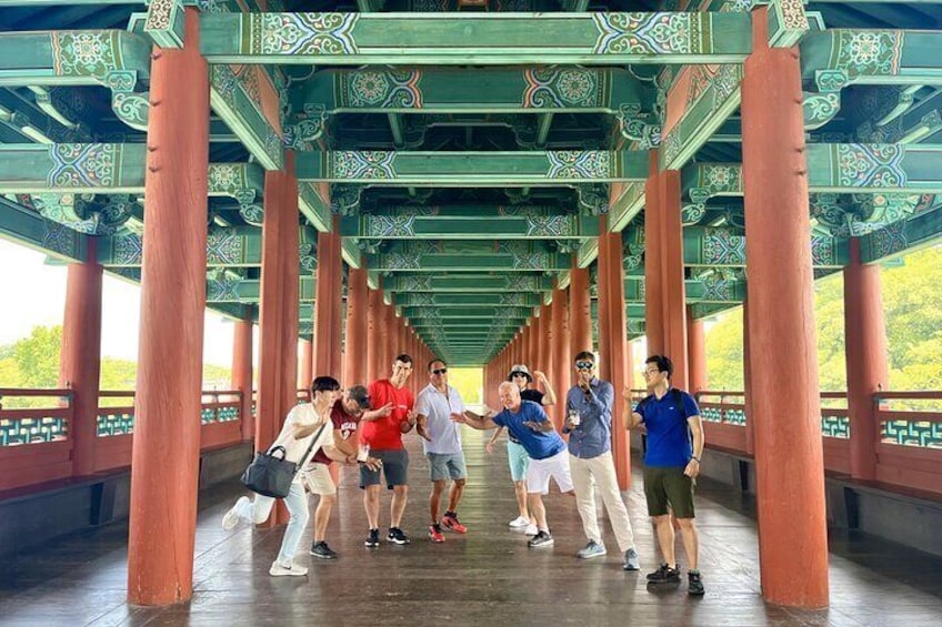 A group of people standing under a traditional architectural structure with ornate designs. 1