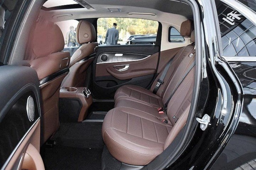 A car interior with brown leather seats, a center console, and a rearview mirror. 3