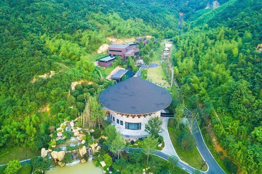 A circular building surrounded by lush greenery and a winding road. 1
