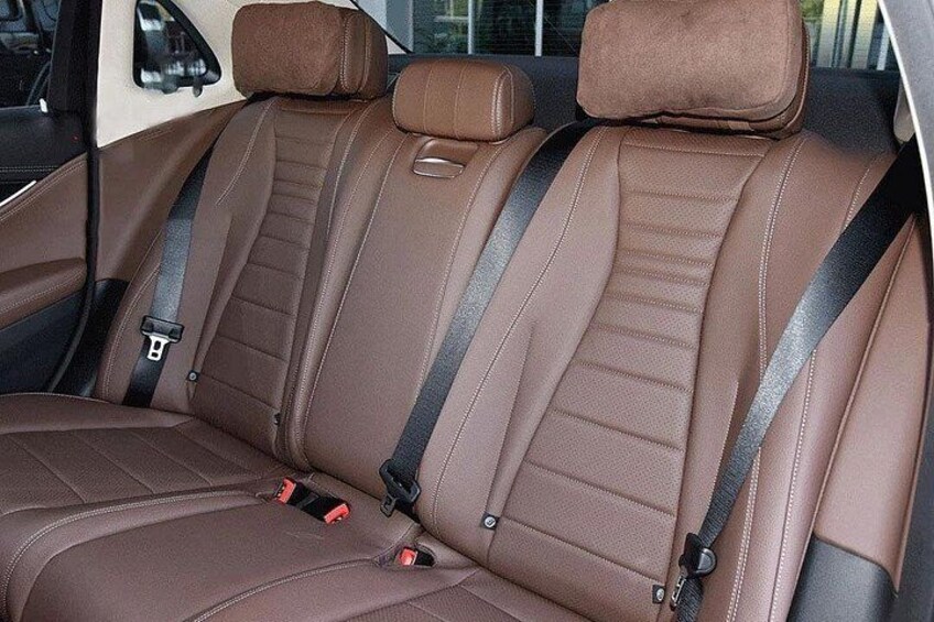 A car interior with brown leather seats and seat belts. 2