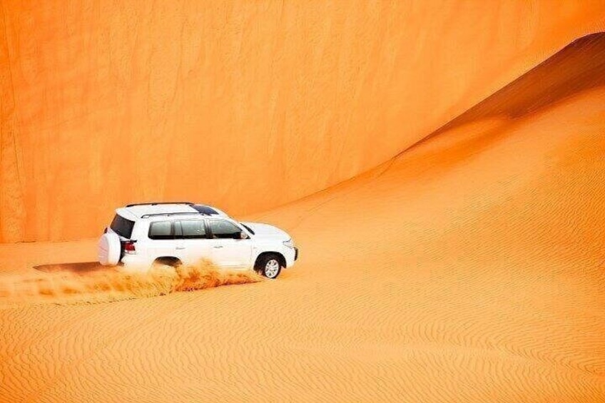 A white SUV driving through a desert with sand dunes. 2