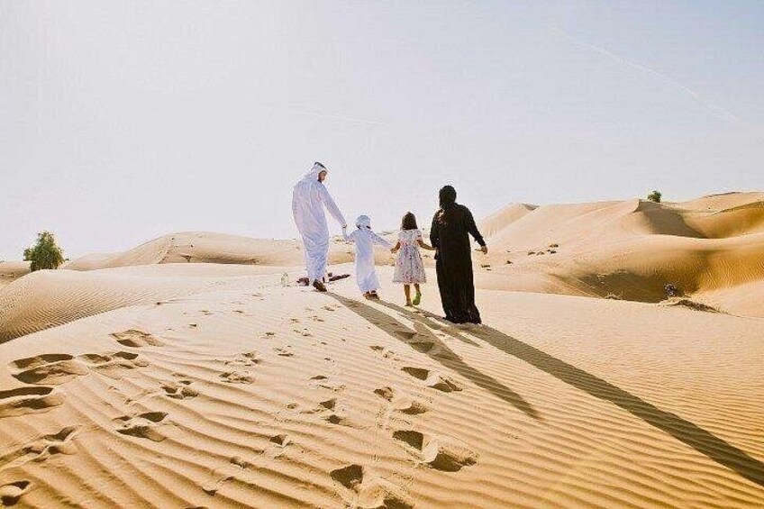 A family walking on a sandy dune in a desert landscape. 4
