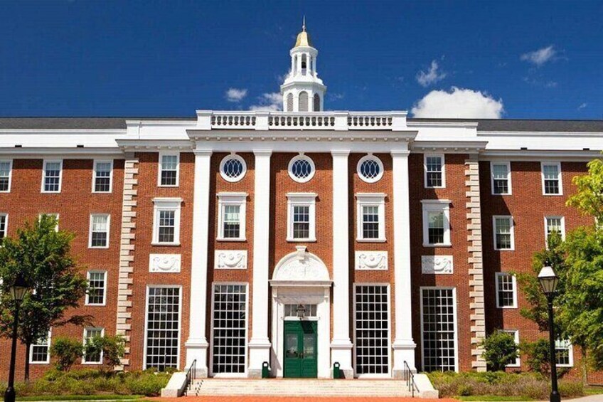 A red brick building with white trim, a central entrance, and a clock tower. 1