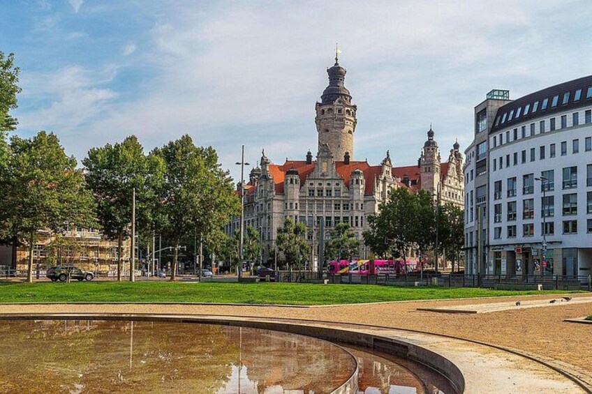 Een historisch gebouw met een toren, een modern gebouw en een fontein in een park. 3