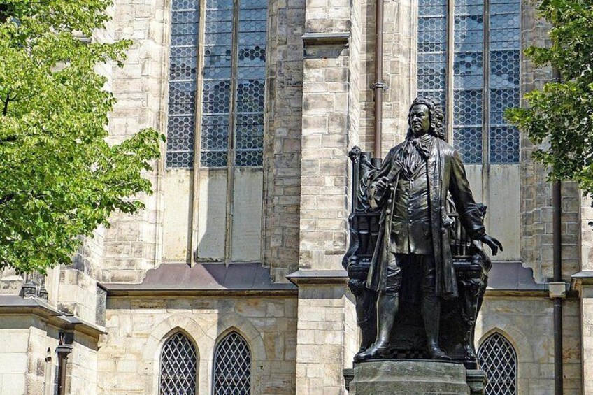 Een standbeeld van een historische figuur voor een gebouw van steen met ronde ramen. 5