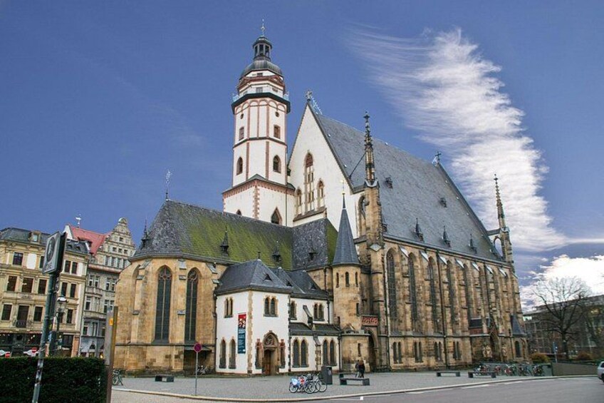 Een historisch kerkgebouw met een opvallende toren en een groot gebouw met een steile kap. 4