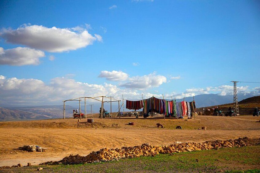 A rural landscape with a dirt road, a small structure, and a pile of stones. 4