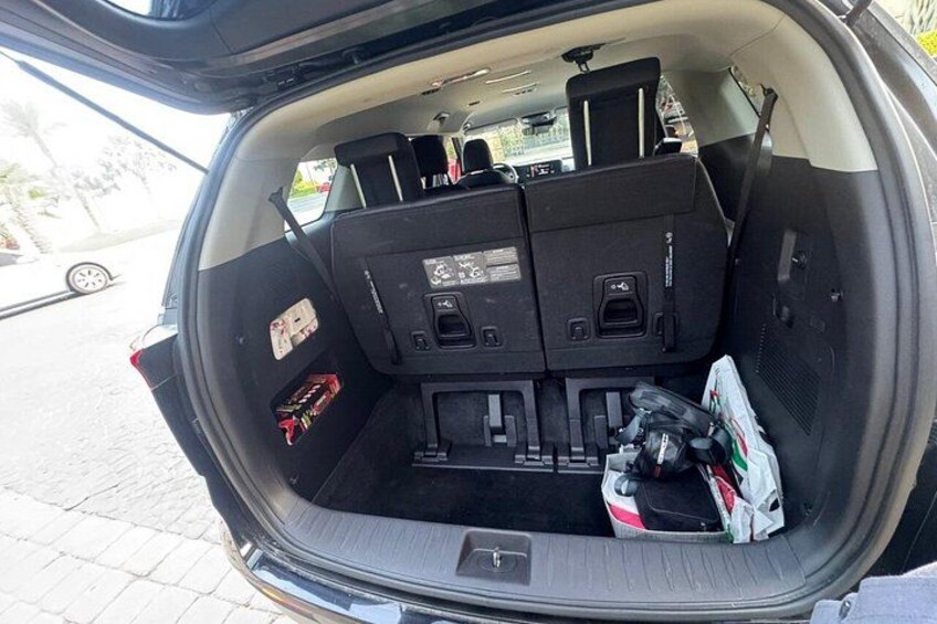 A car's trunk open with a toolbox and a bag of groceries visible. 2
