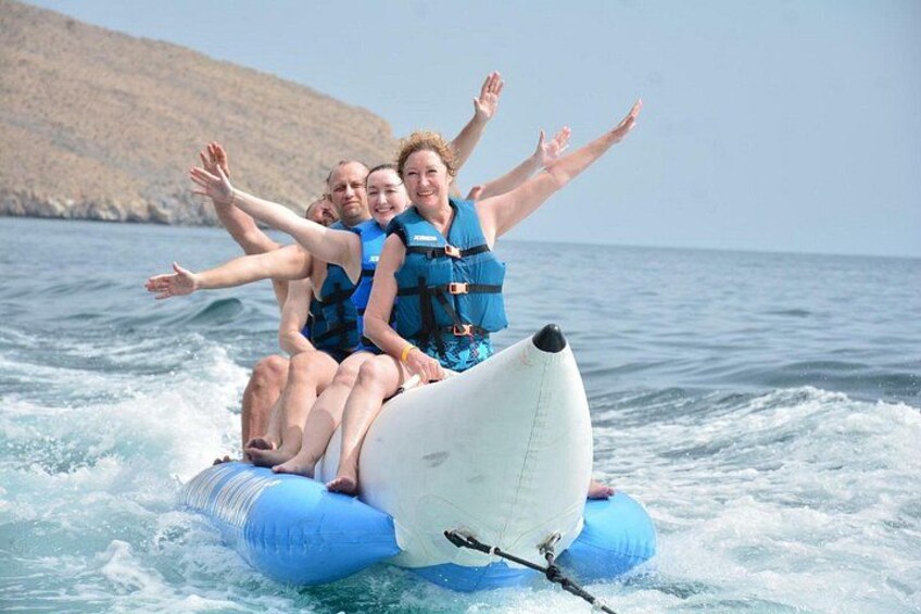 People on a white raft with blue life jackets, floating on water with waves. 1