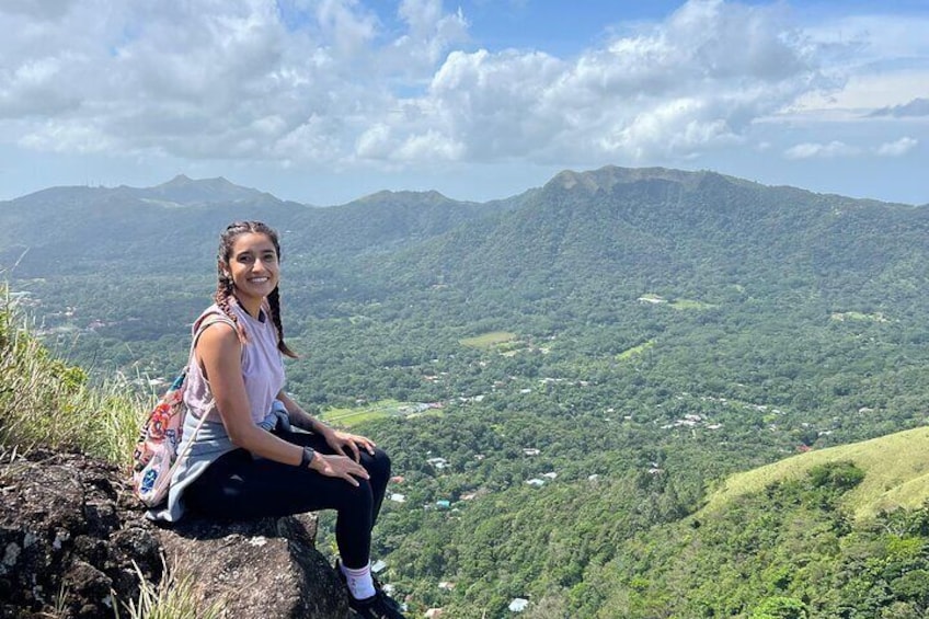 A person sitting on a rock with a mountainous landscape in the background. 1