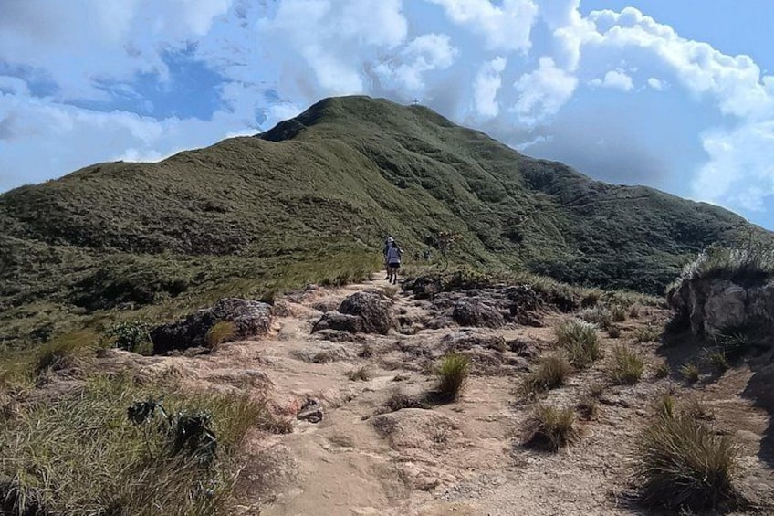 A person hiking on a dirt path with a mountain in the background. 2