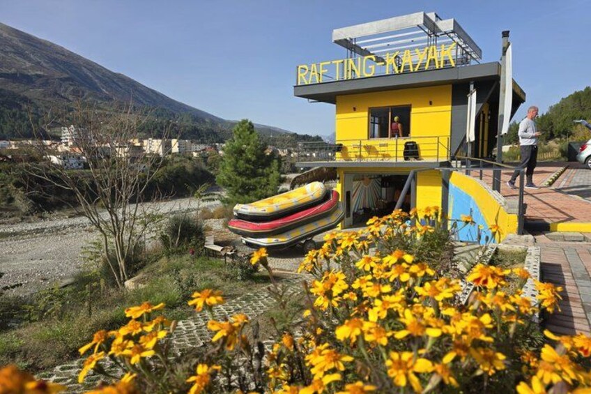 A yellow building labeled 'RAFTING KAYAK' with a mountain in the background. 5