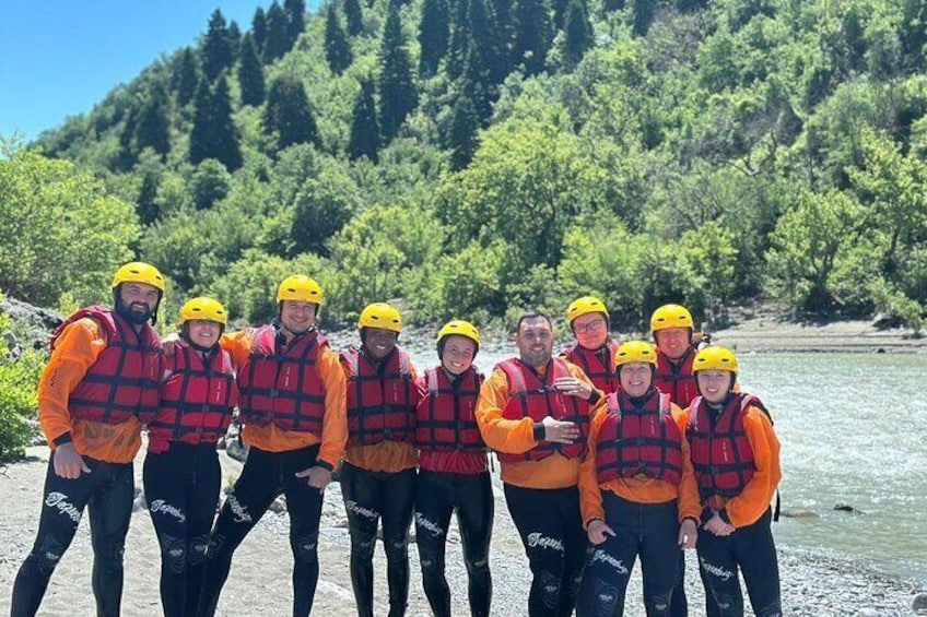 A group of people wearing life jackets and helmets by a river. 2