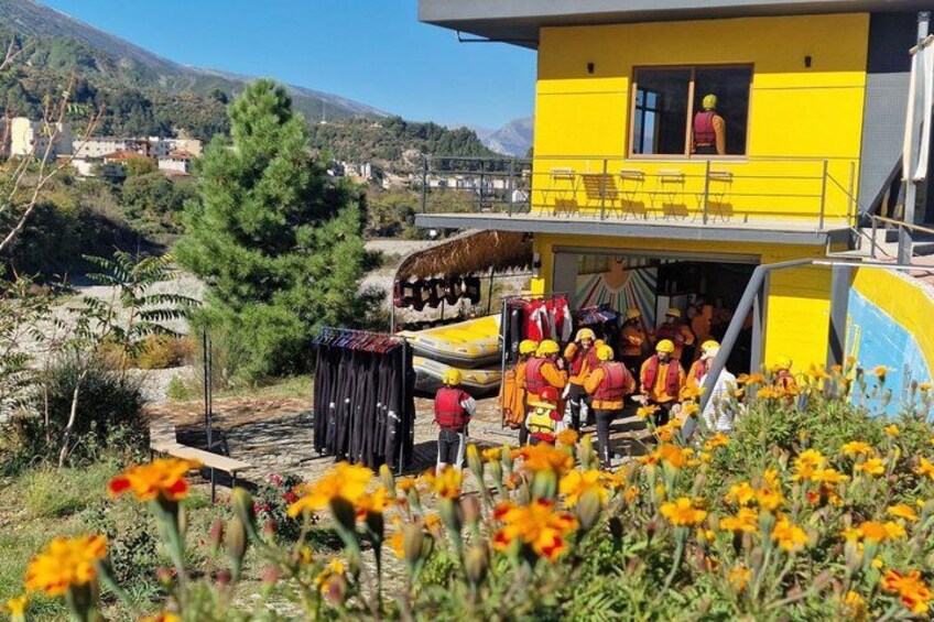 A yellow building with a balcony, surrounded by flowers and trees. 3