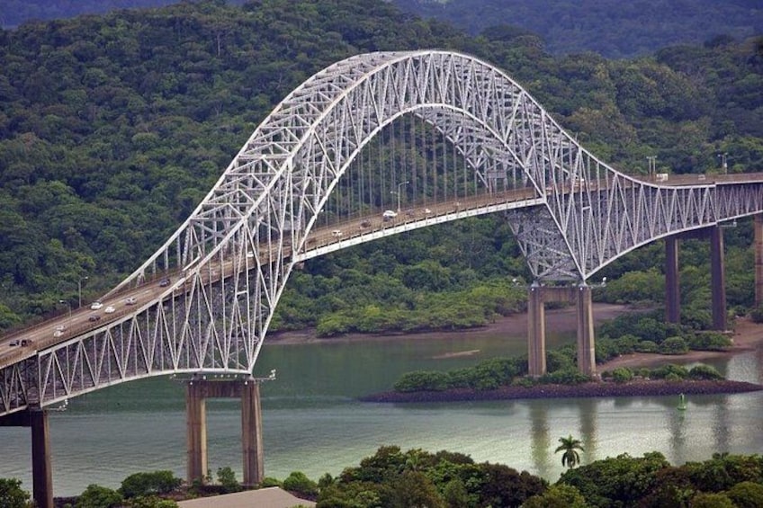 A steel truss bridge over a river with dense forest in the background. 2