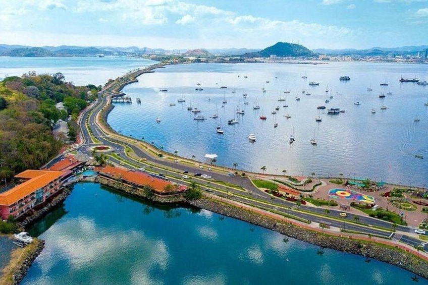 A coastal city with a marina filled with boats, a curved road, and a park with colorful patterns. 4