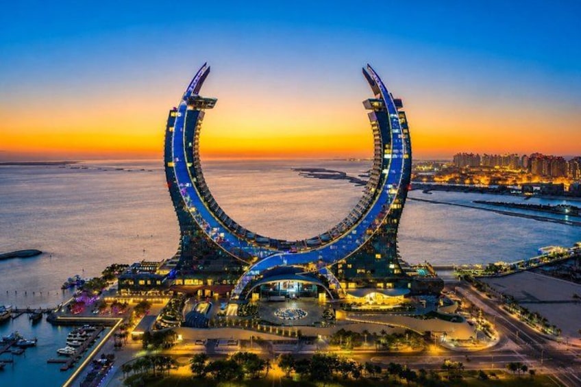 A waterfront structure with a curved design, surrounded by a marina and cityscape. 2