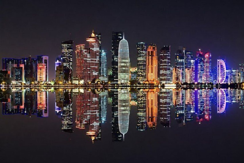 Een verlicht stadsbeeld bij nacht, met gebouwen die in het water worden weerspiegeld. 3