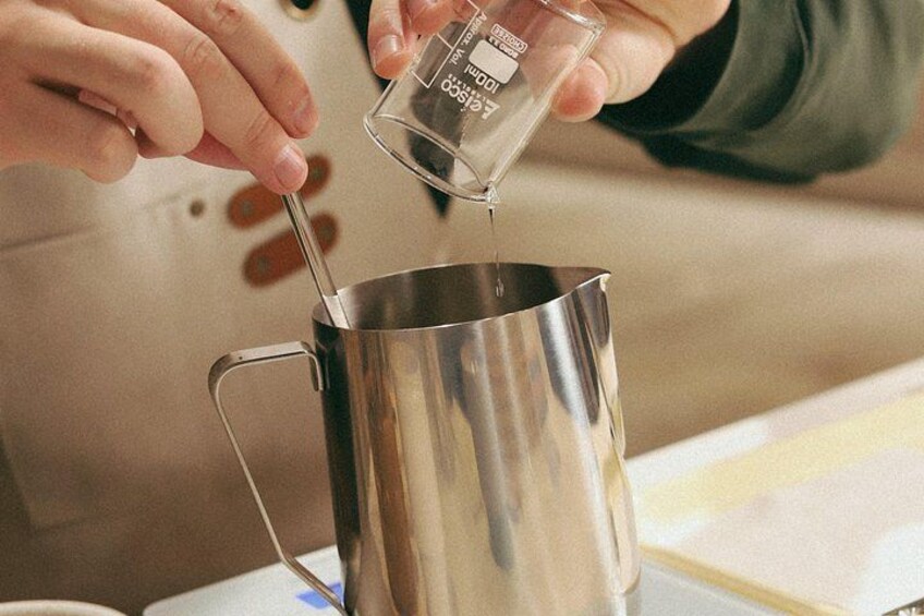 Una persona vertiendo líquido desde una taza medidora a una olla de acero inoxidable. 2